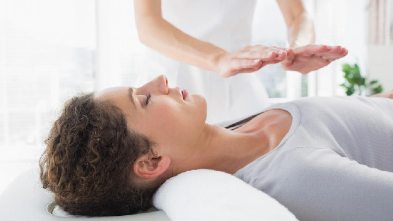 Fotografia de uma moça recebendo o tratamento de Reiki.